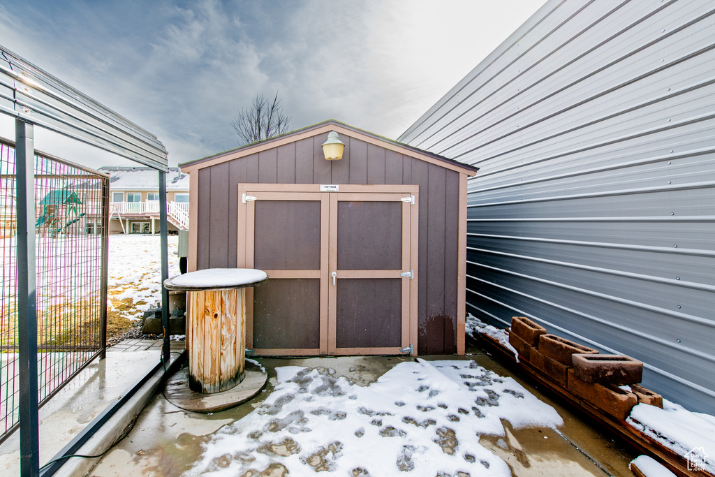 Snow covered structure with a storage shed, an outdoor structure, and fence
