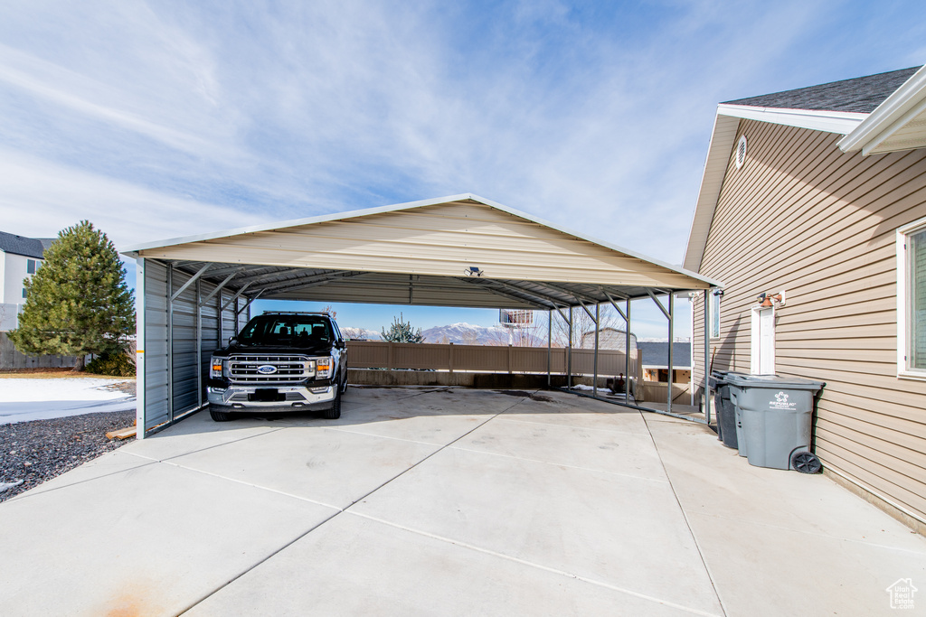 View of car parking with fence, a carport, and concrete driveway