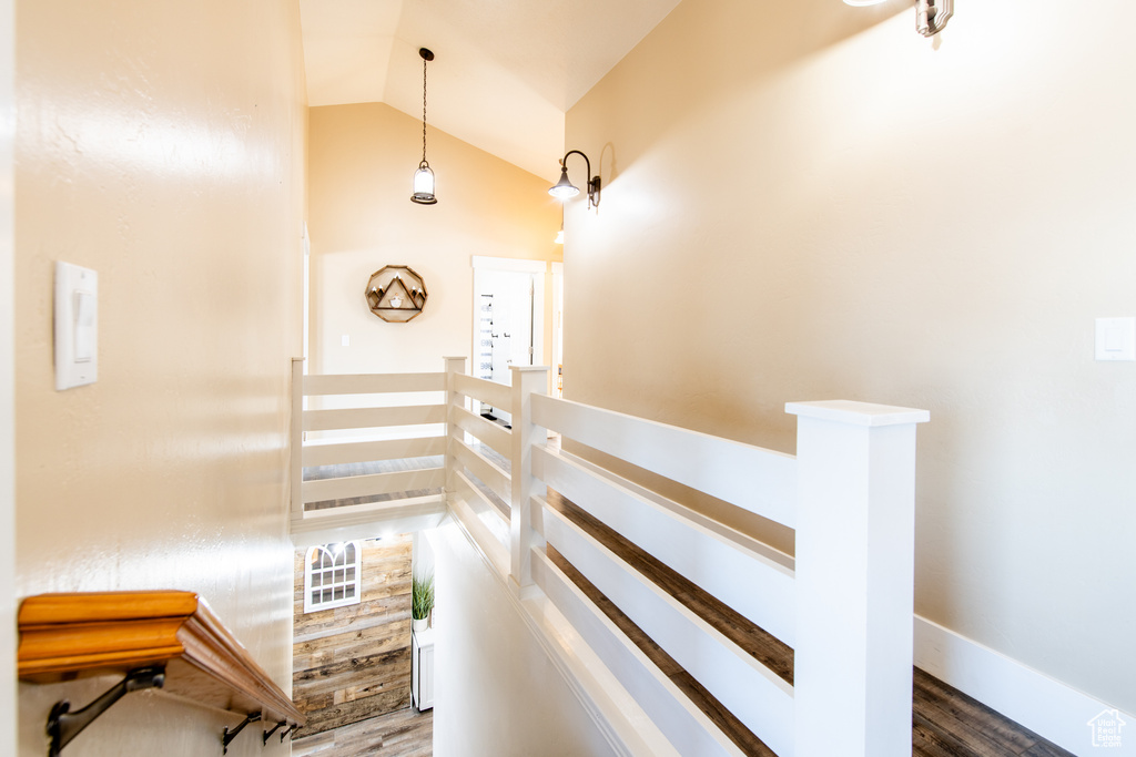 Staircase with vaulted ceiling, wood finished floors, and baseboards