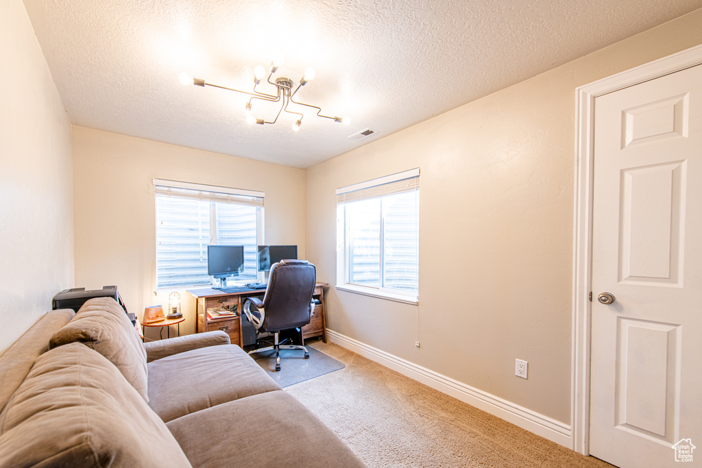 Office space featuring a textured ceiling, a chandelier, light carpet, visible vents, and baseboards