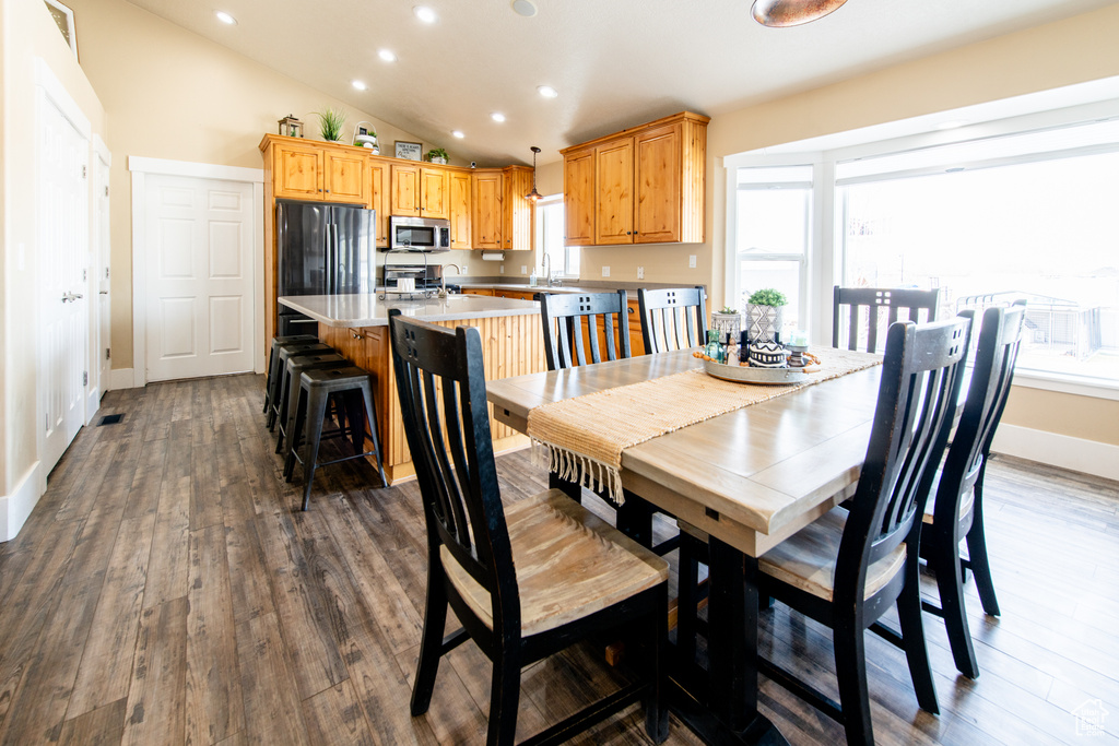 Dining room with vaulted ceiling, dark wood-style floors, and a healthy amount of sunlight