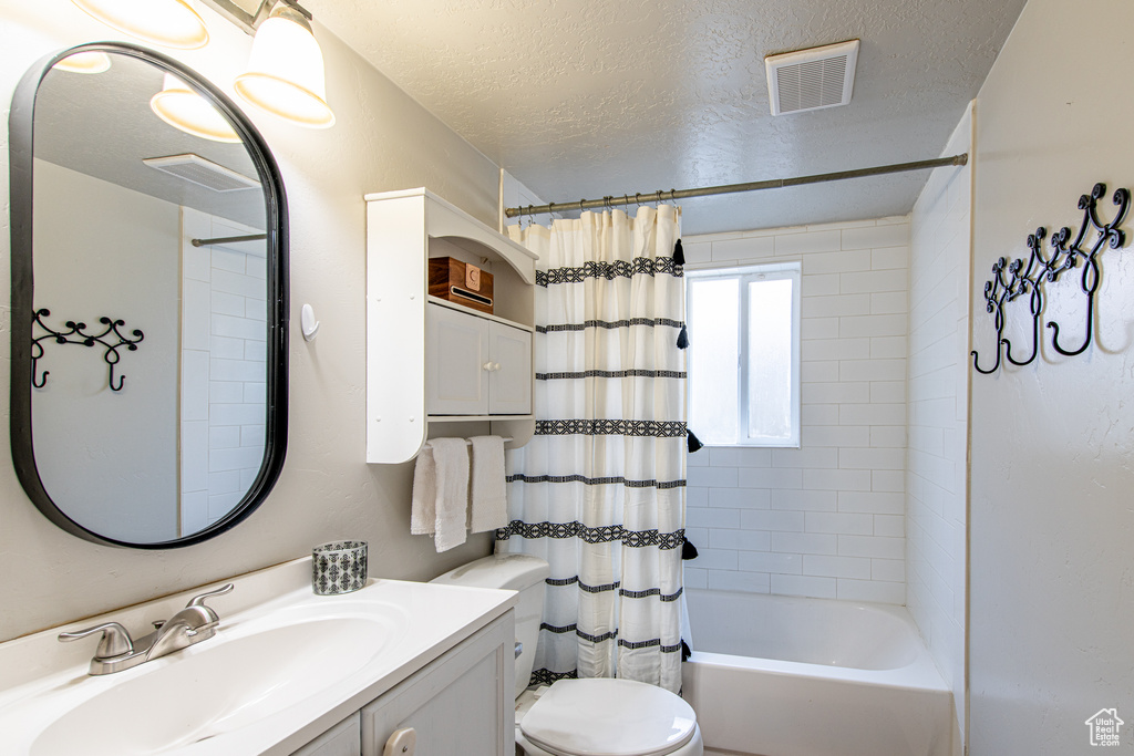 Full bath featuring a textured ceiling, toilet, vanity, visible vents, and shower / bathtub combination with curtain
