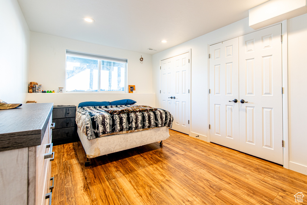 Bedroom featuring light wood finished floors, baseboards, multiple closets, and recessed lighting