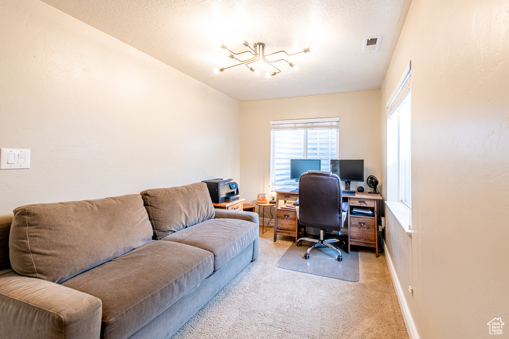 Office with light carpet, baseboards, visible vents, a textured ceiling, and a notable chandelier