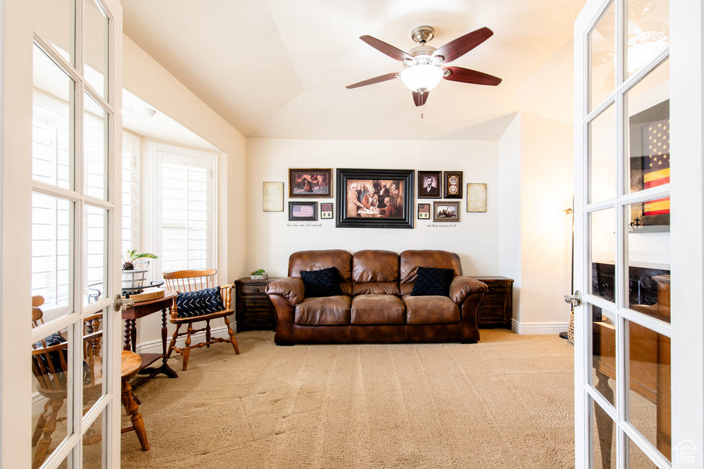 Carpeted living area featuring ceiling fan, baseboards, and french doors