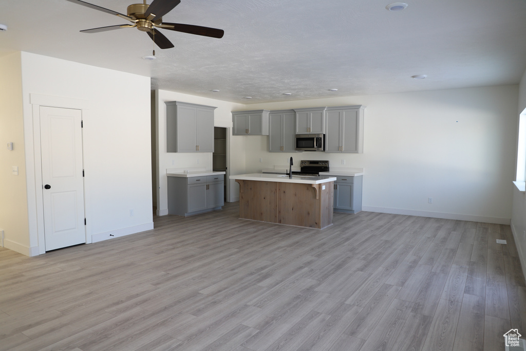 Kitchen featuring open floor plan, stainless steel appliances, gray cabinets, and light wood-style floors