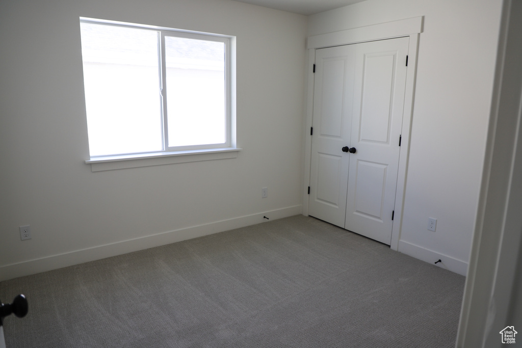 Unfurnished bedroom with light carpet and baseboards
