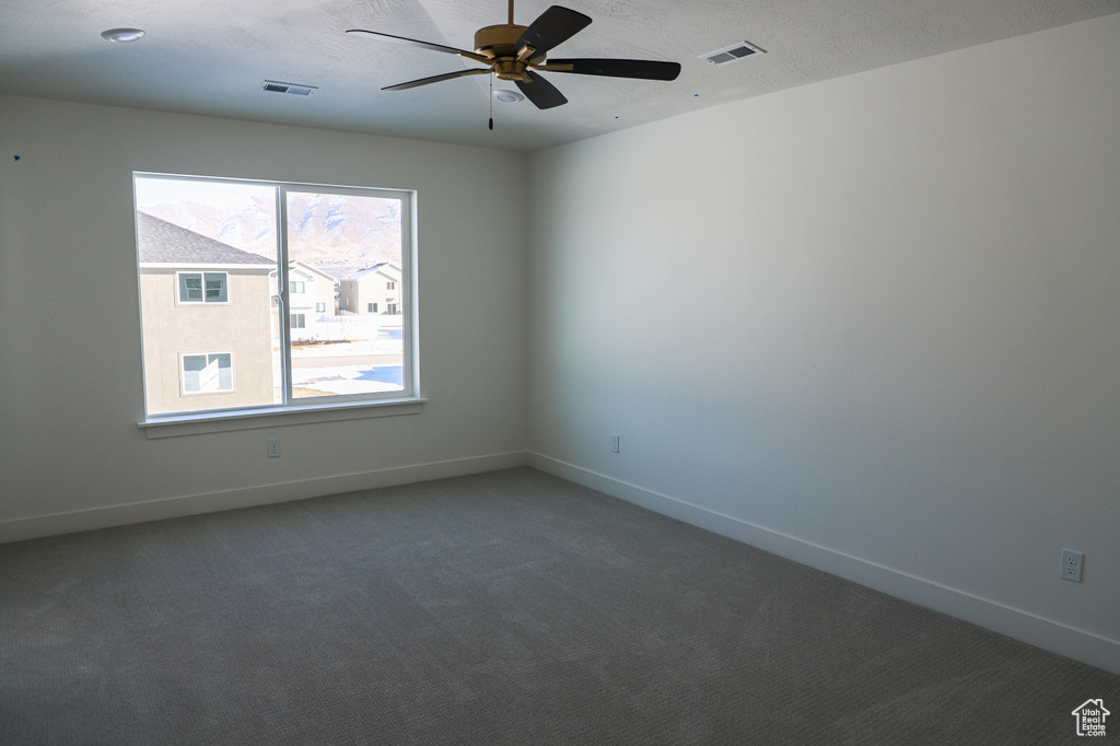 Spare room featuring a ceiling fan, carpet, visible vents, and baseboards