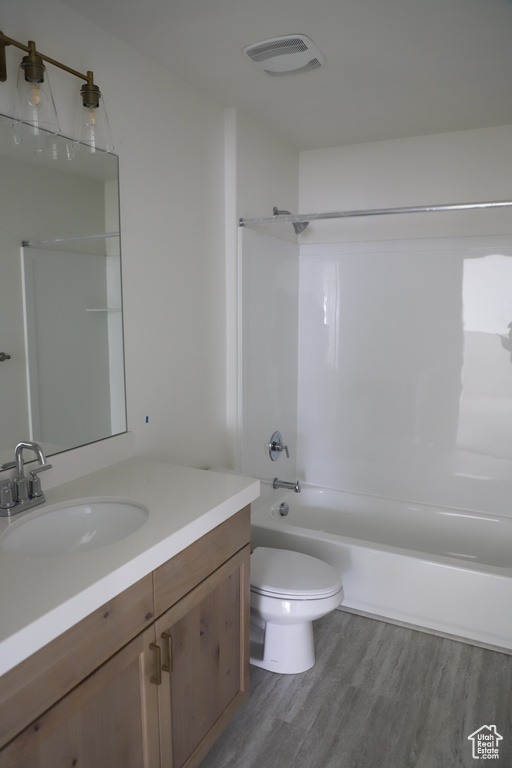 Full bath featuring toilet, wood finished floors, vanity, visible vents, and shower / washtub combination