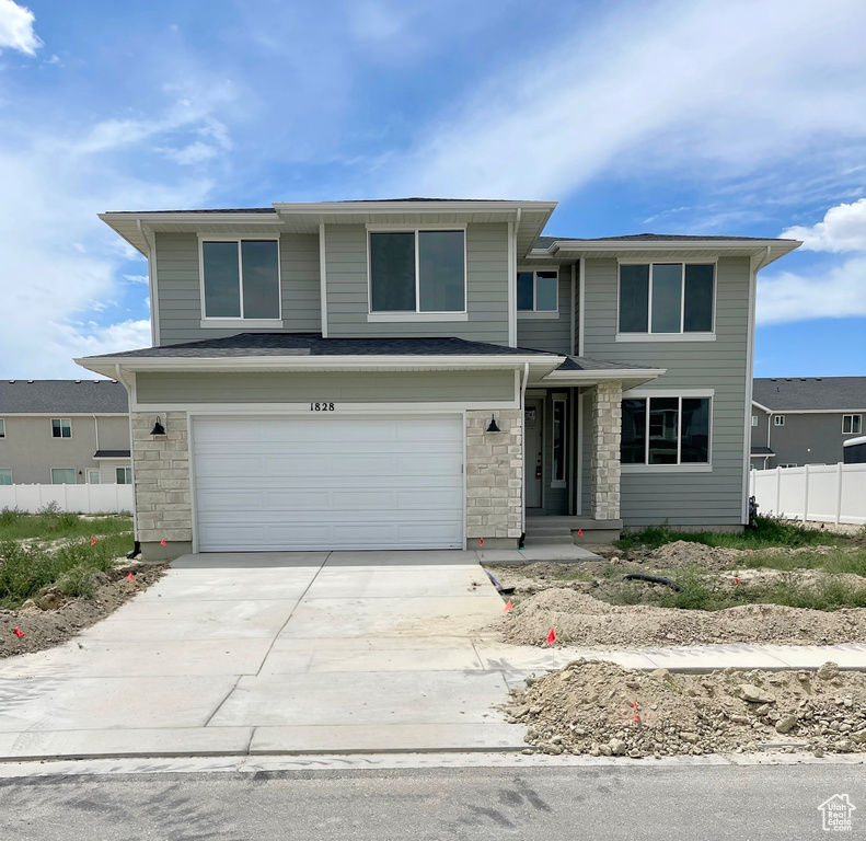 View of front of house with an attached garage, stone siding, and concrete driveway