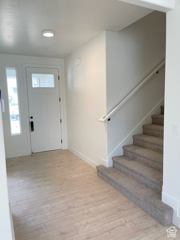 Foyer with stairs and light wood finished floors