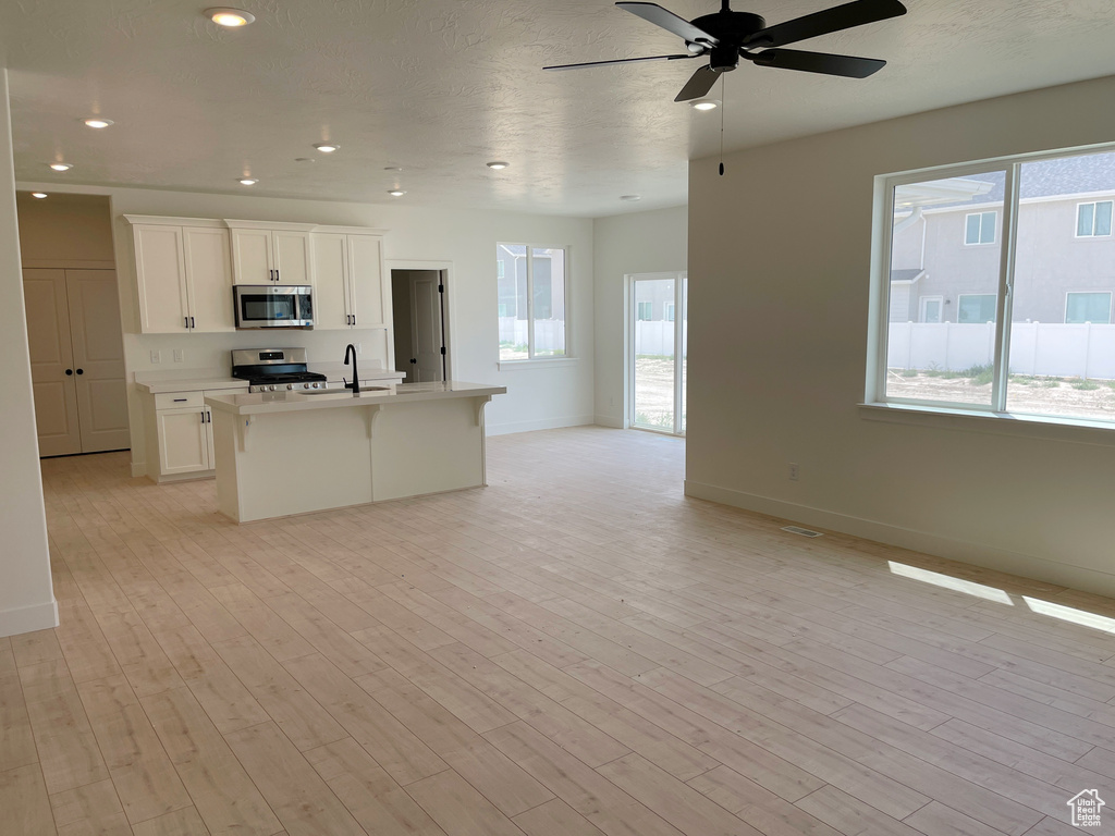 Kitchen featuring appliances with stainless steel finishes, open floor plan, healthy amount of natural light, a center island with sink, and recessed lighting