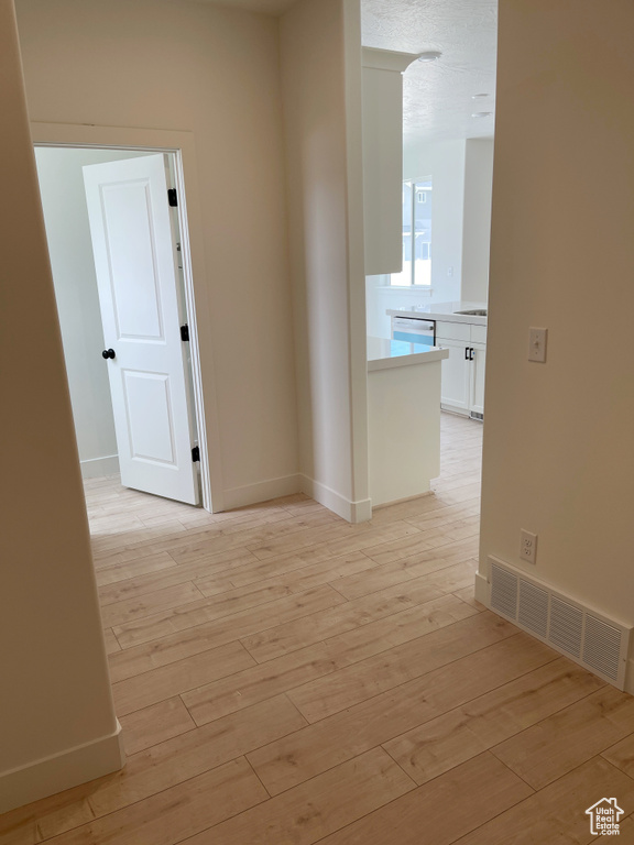 Corridor featuring light wood-style flooring and baseboards