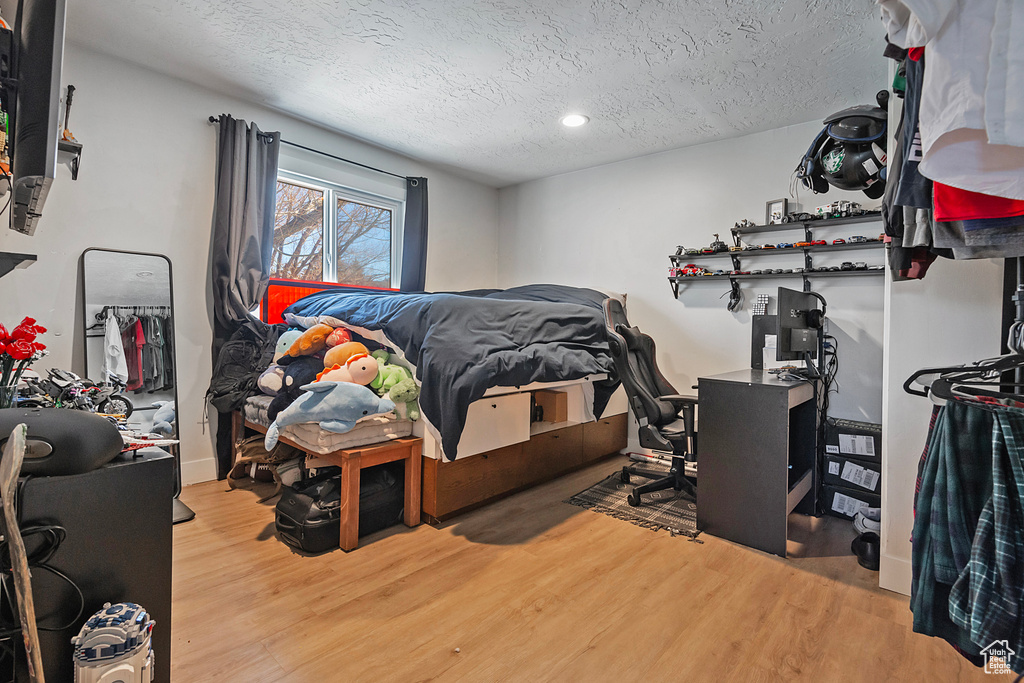Bedroom with a textured ceiling and wood finished floors