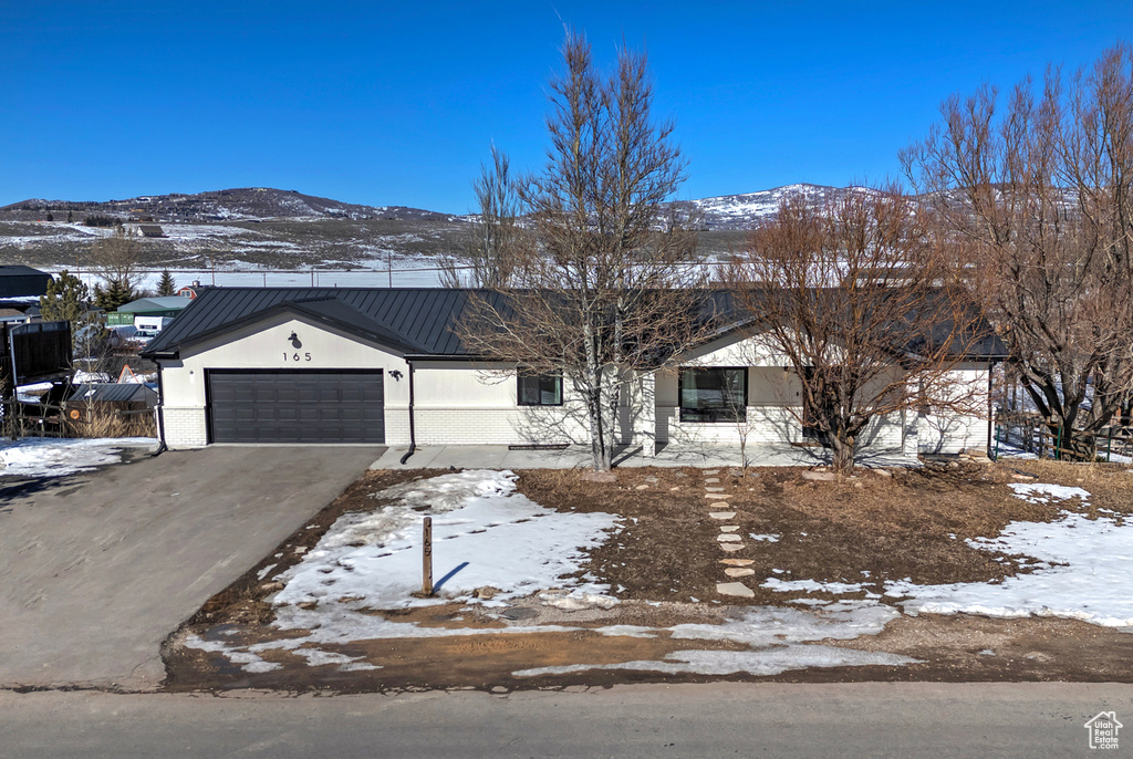 Ranch-style home featuring metal roof, an attached garage, a mountain view, brick siding, and a standing seam roof
