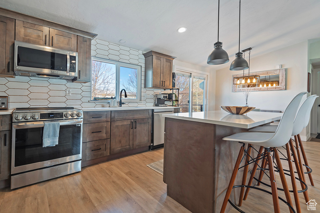Kitchen featuring stainless steel appliances, light countertops, a sink, and light wood-style flooring