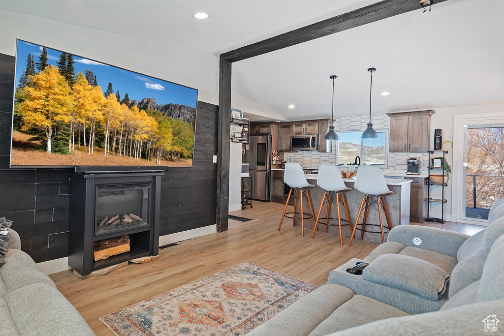 Living room featuring light wood-type flooring, lofted ceiling with beams, baseboards, and recessed lighting
