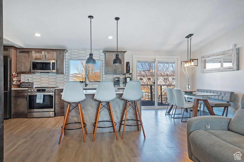 Kitchen featuring stainless steel appliances, light wood finished floors, backsplash, and light countertops