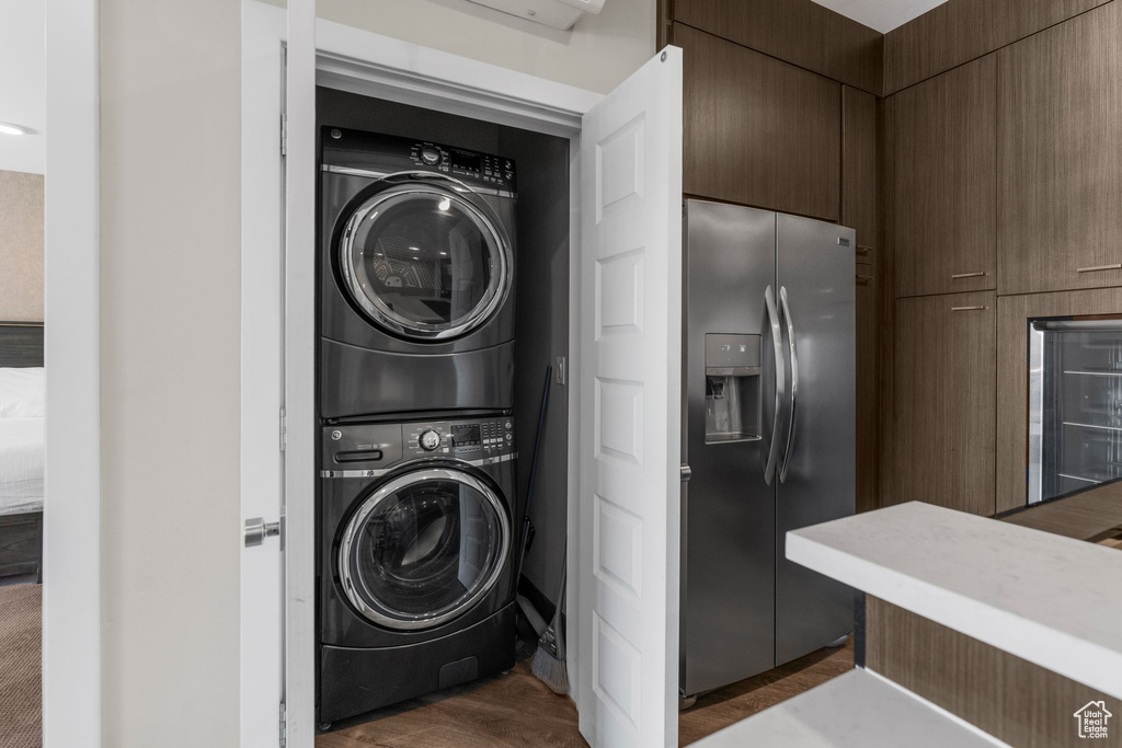 Laundry room with stacked washer and dryer, wine cooler, and laundry area
