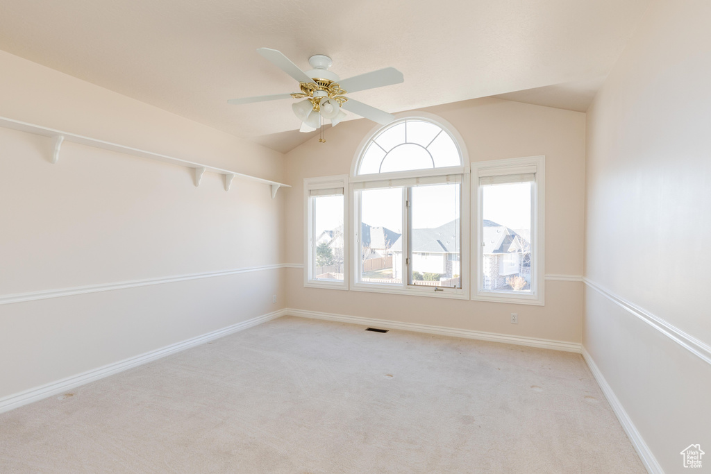 Spare room with visible vents, a ceiling fan, light carpet, vaulted ceiling, and baseboards