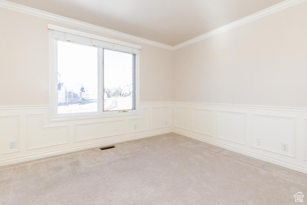 Carpeted empty room featuring ornamental molding, a wainscoted wall, and visible vents