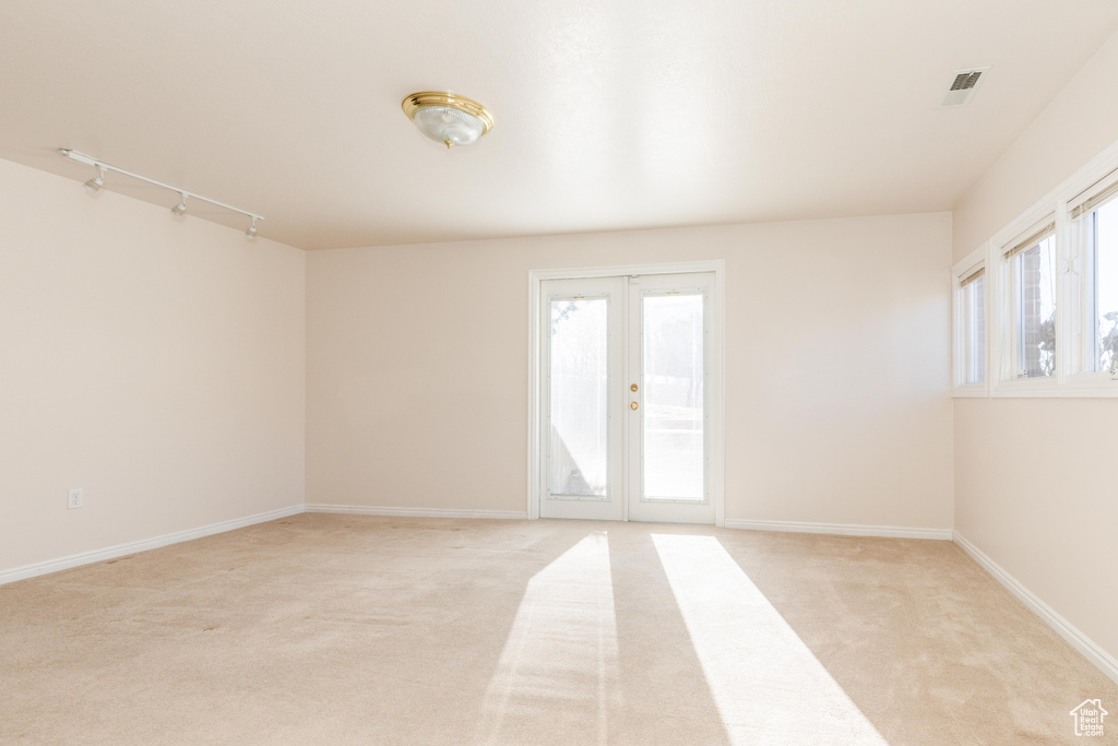 Spare room with french doors, light carpet, visible vents, and baseboards