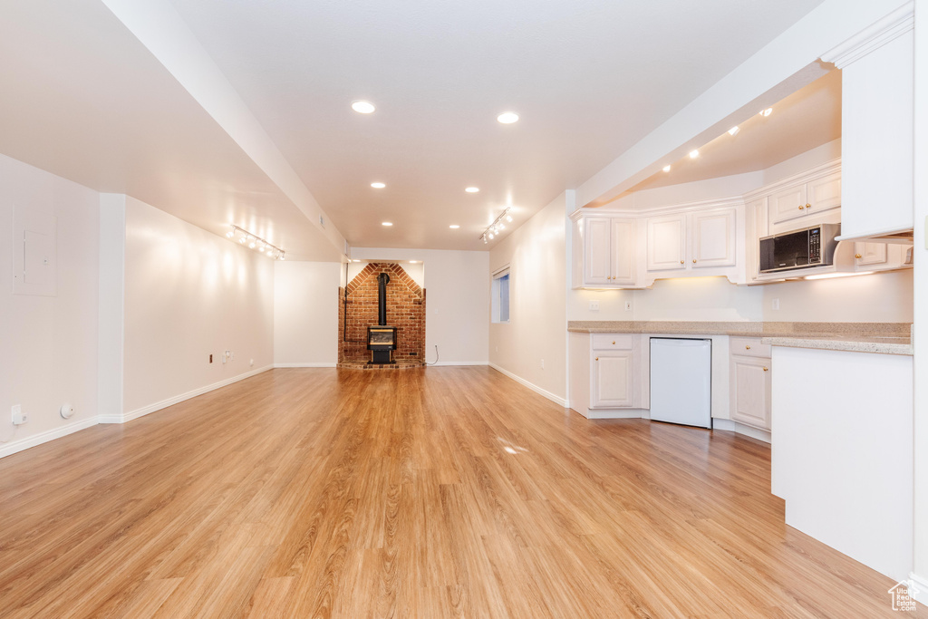 Unfurnished living room with baseboards, recessed lighting, a wood stove, and light wood-style floors