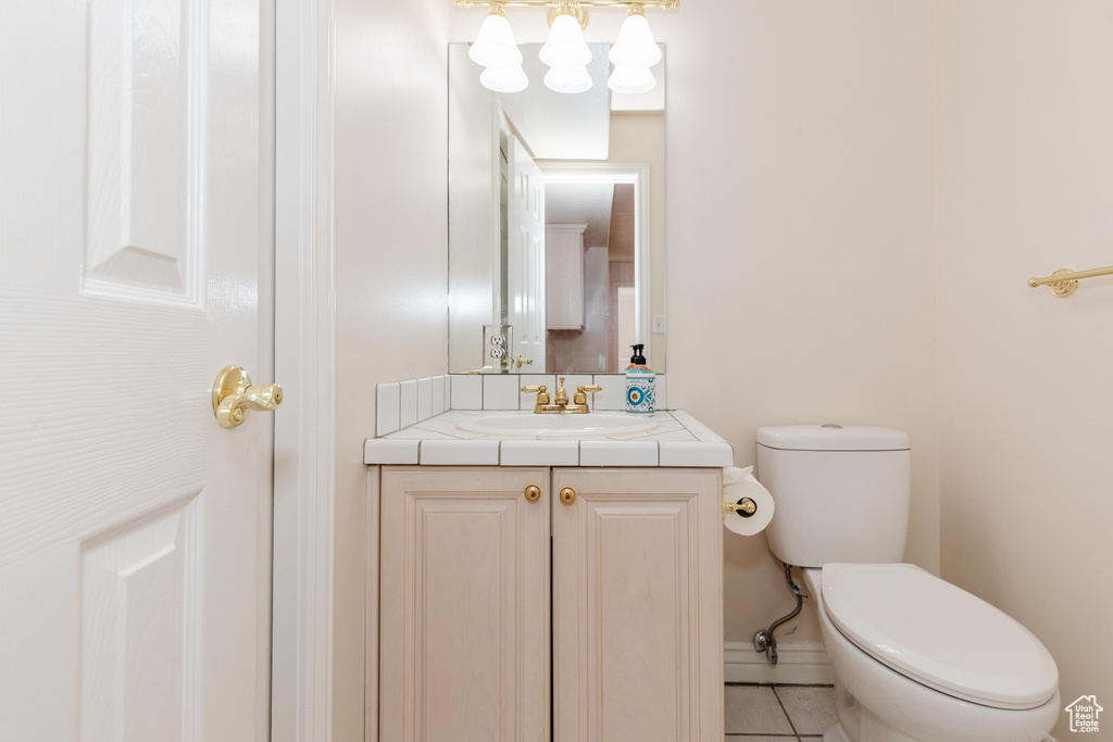 Bathroom featuring baseboards, vanity, toilet, and tile patterned floors