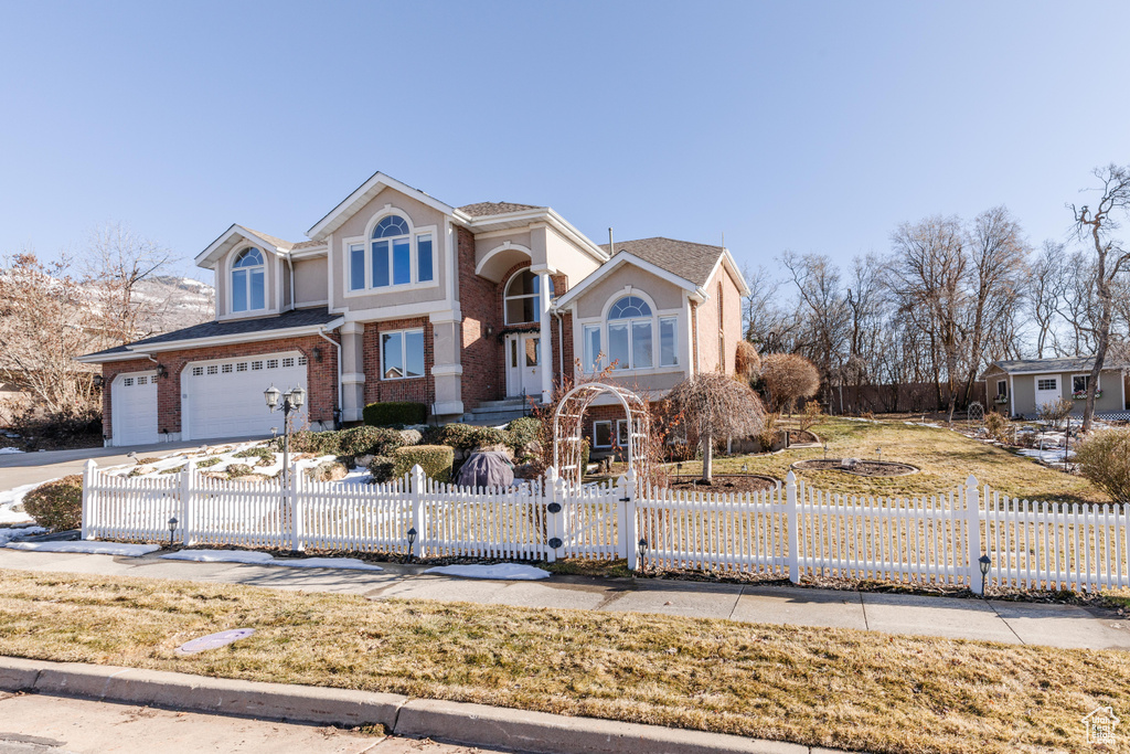 View of front facade featuring a fenced front yard, a gate, brick siding, and an attached garage