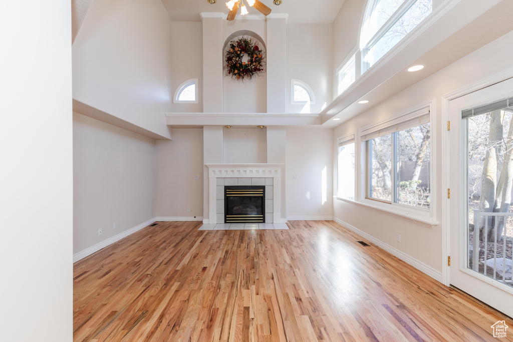 Unfurnished living room featuring plenty of natural light, a fireplace, wood finished floors, and baseboards