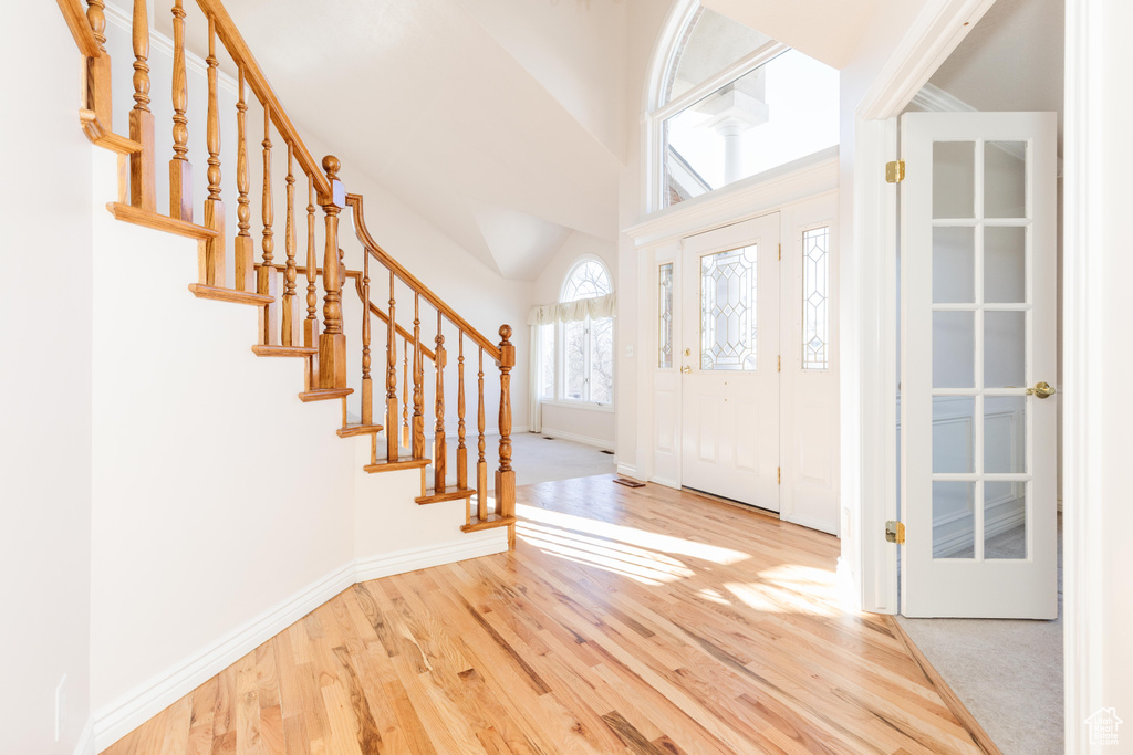 Entrance foyer featuring a towering ceiling, stairs, baseboards, and wood finished floors