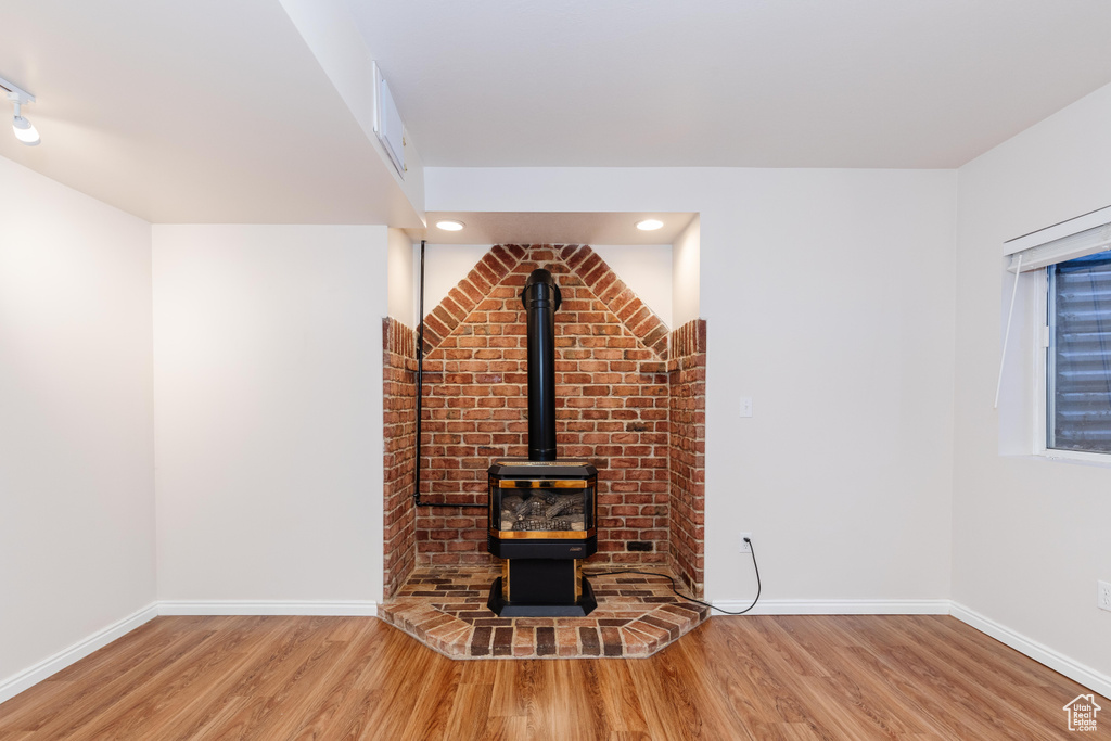 Unfurnished living room featuring wood finished floors, a wood stove, and baseboards