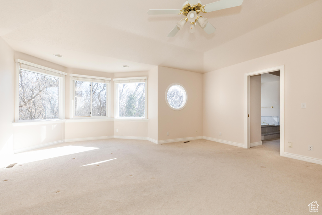 Spare room featuring light carpet, ceiling fan, and baseboards