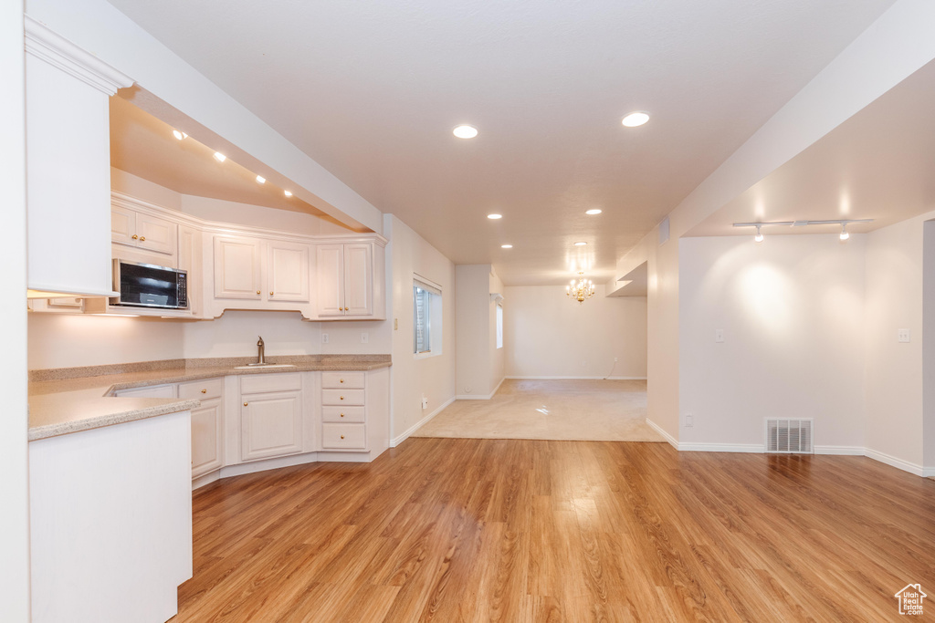 Kitchen with a sink, visible vents, open floor plan, light countertops, and light wood-type flooring