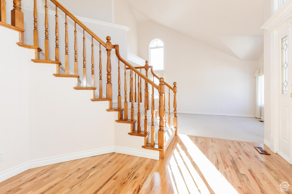 Interior space with high vaulted ceiling, baseboards, visible vents, and wood finished floors