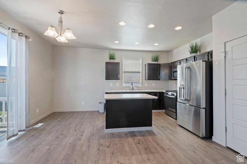Kitchen with stainless steel appliances, light countertops, light wood-style floors, a center island, and recessed lighting