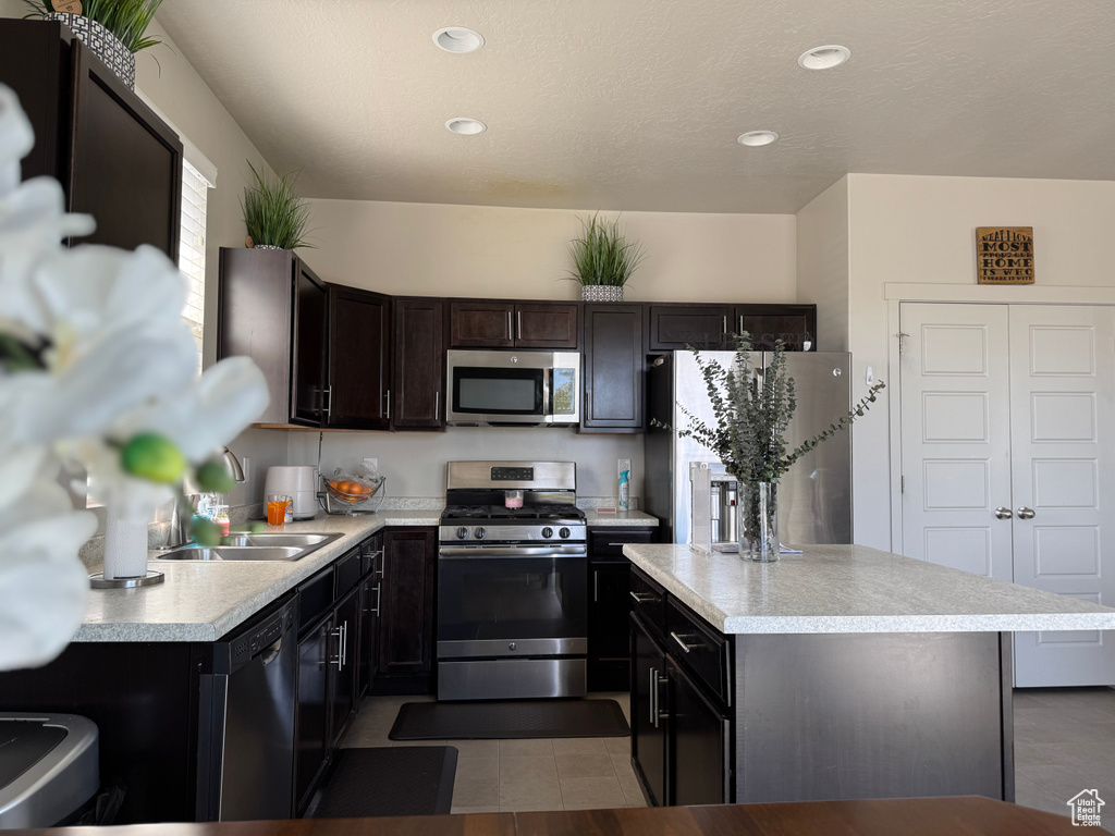 Kitchen featuring a sink, stainless steel appliances, light countertops, a kitchen island, and recessed lighting