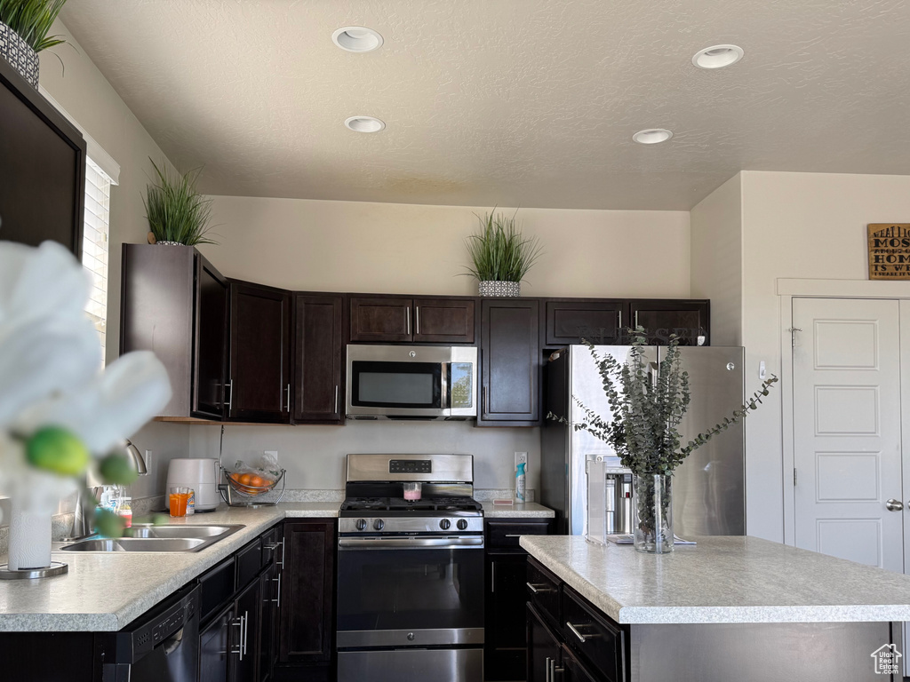 Kitchen featuring a sink, stainless steel appliances, light countertops, a kitchen island, and recessed lighting