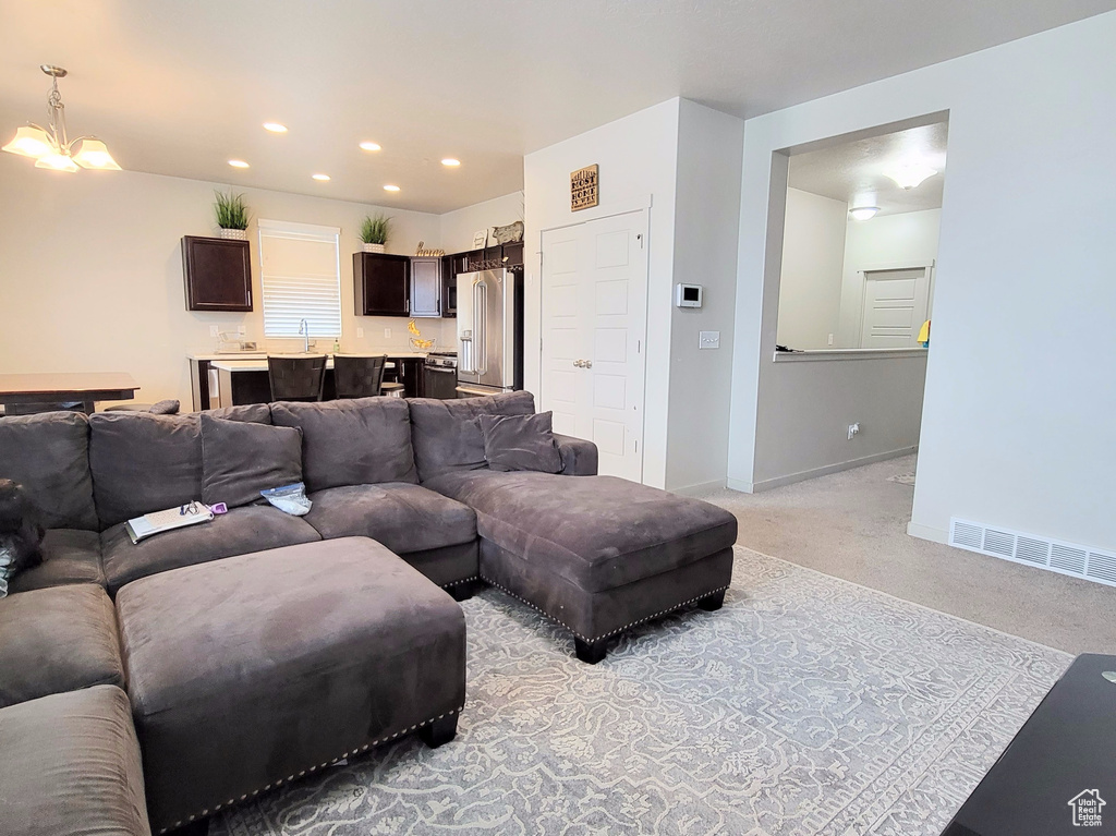 Living room featuring light carpet, baseboards, visible vents, an inviting chandelier, and recessed lighting