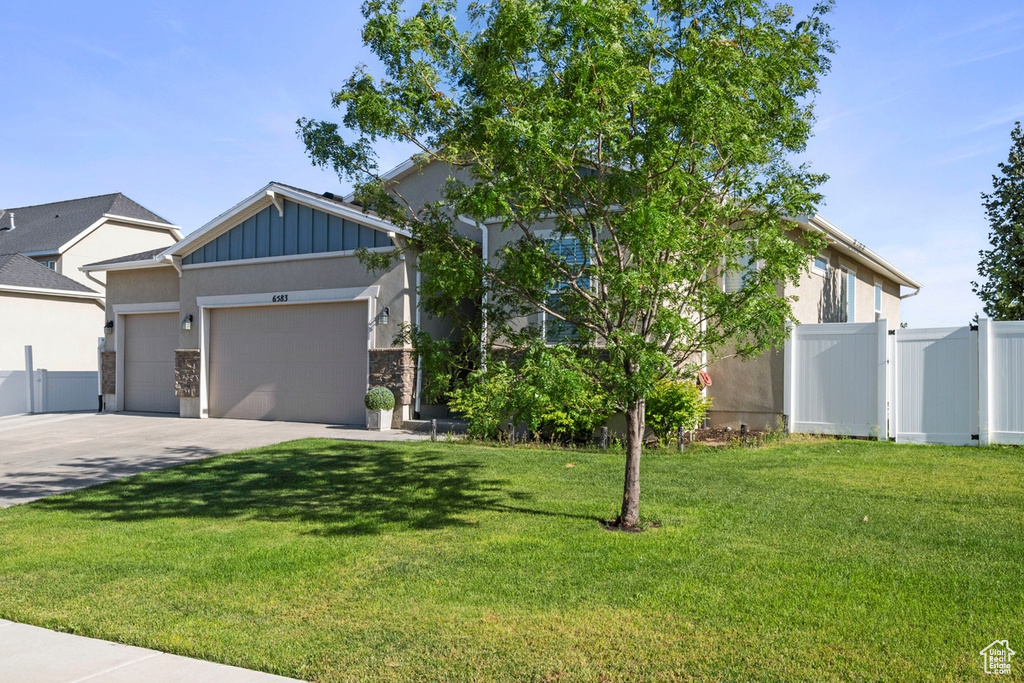 View of front of home featuring an attached garage, board and batten siding, driveway, and a gate