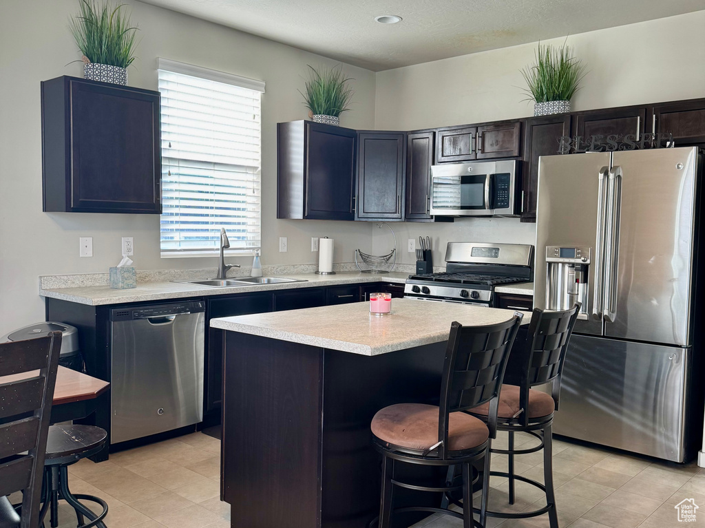 Kitchen featuring a center island, a kitchen breakfast bar, a textured ceiling, stainless steel appliances, and a sink