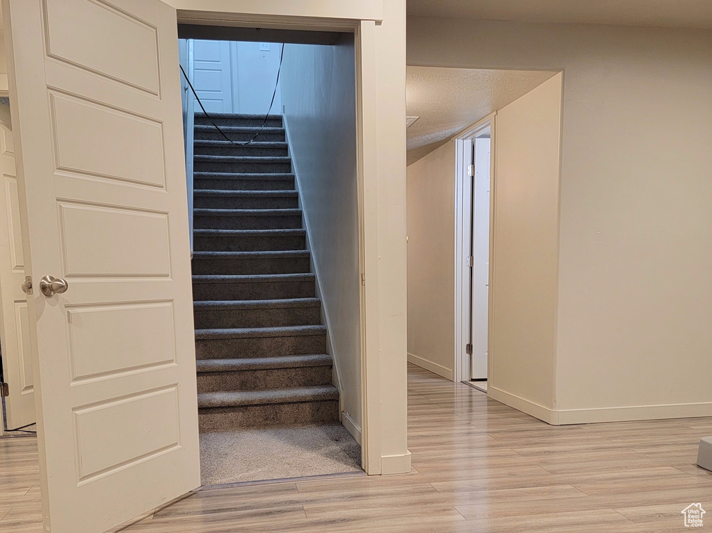 Stairs with recessed lighting, baseboards, and wood finished floors