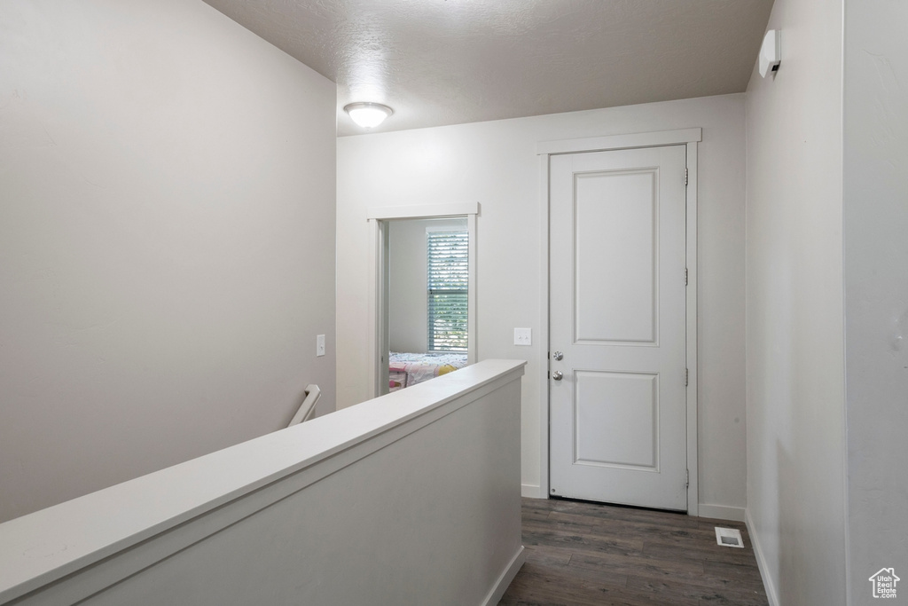 Hall featuring dark wood-style floors and an upstairs landing