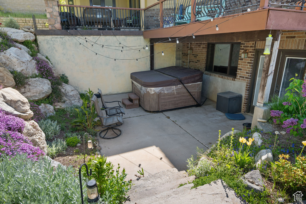 View of patio / terrace with a hot tub and a balcony