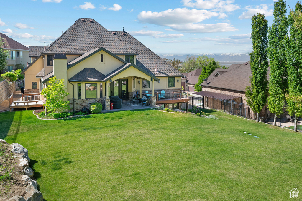 Rear view of house featuring a lawn, a patio, fence, and stucco siding