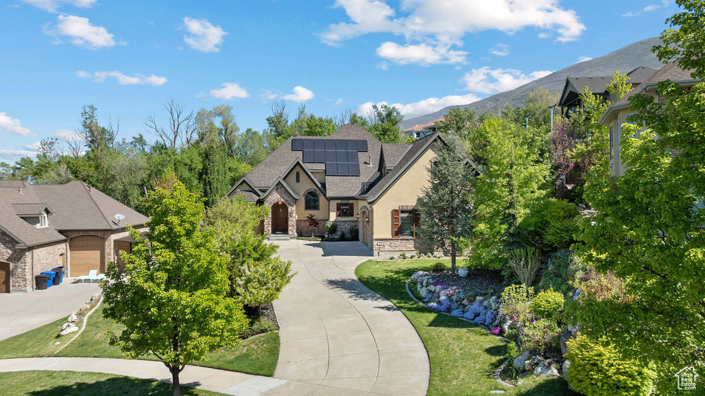 Exterior space featuring solar panels, roof with shingles, a mountain view, stone siding, and stucco siding