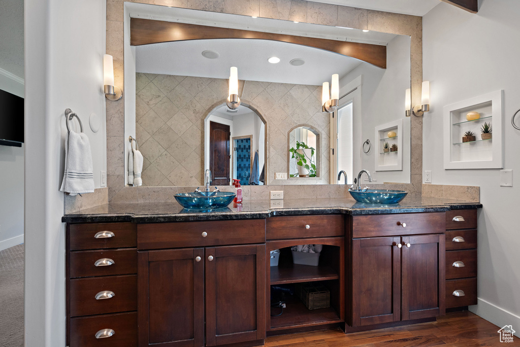Full bathroom featuring a sink, baseboards, double vanity, and wood finished floors