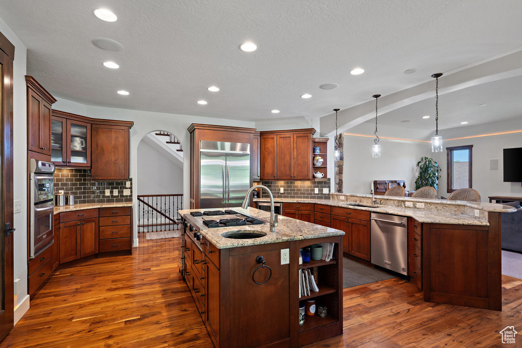 Kitchen with dark wood finished floors, open shelves, stainless steel appliances, and a peninsula