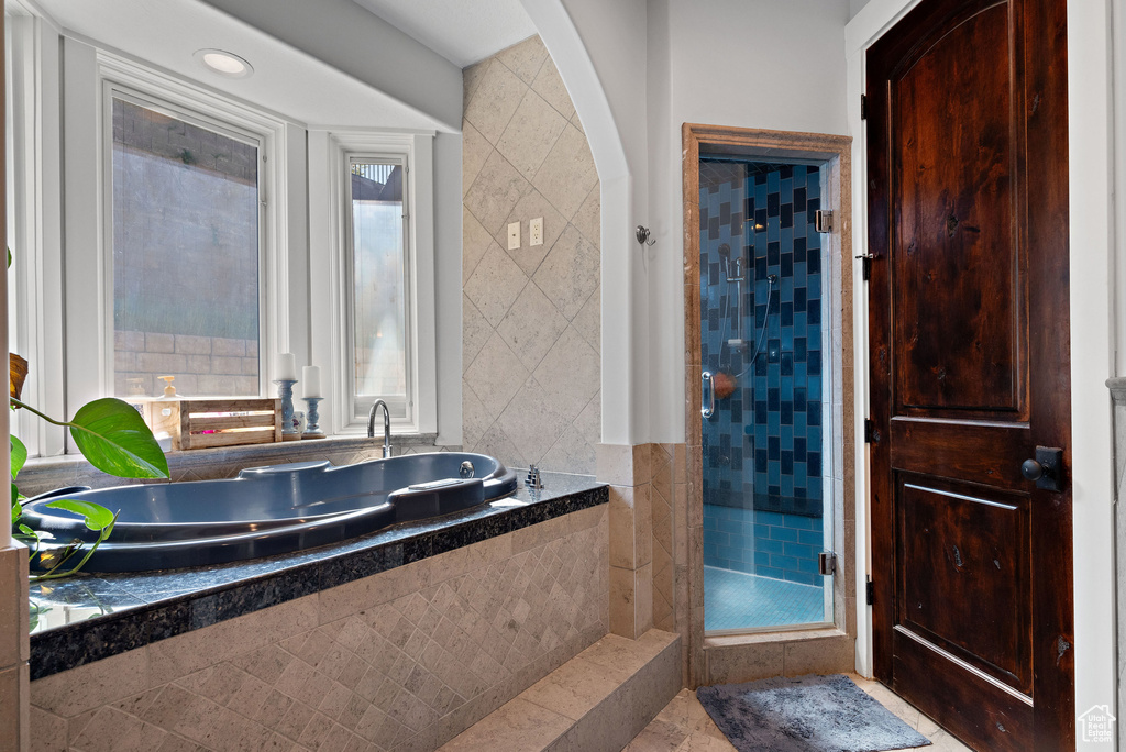 Full bath featuring a bath, tile walls, and a shower stall