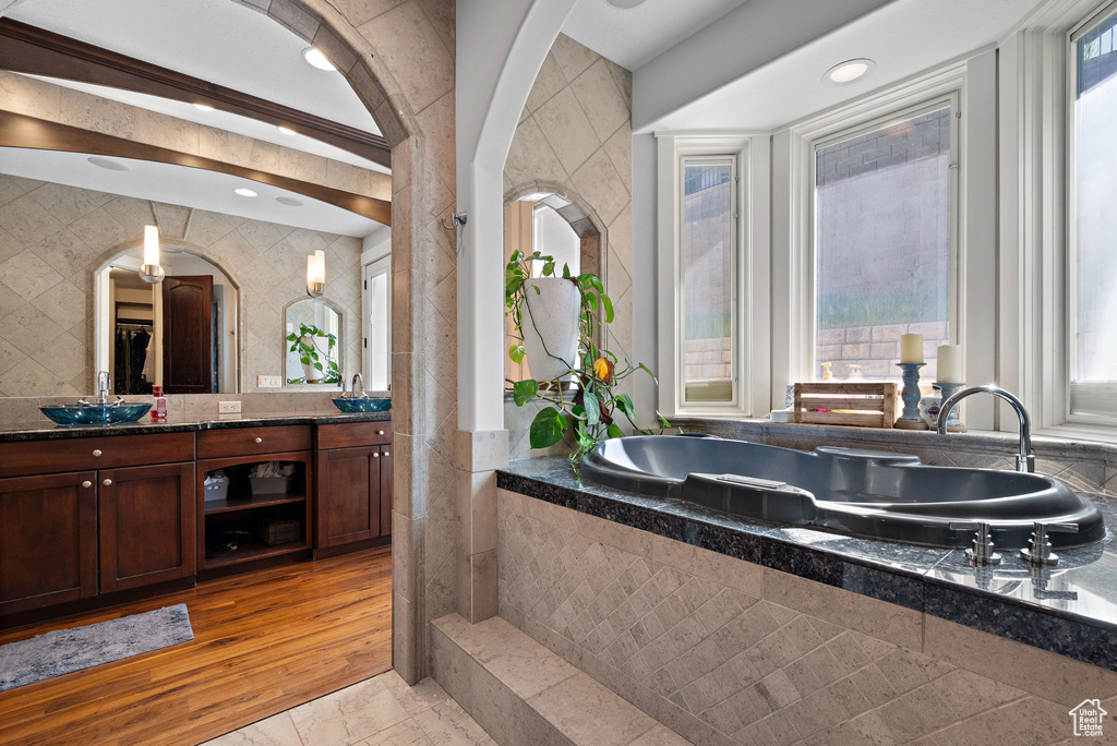 Bathroom with double vanity, a washtub, tile walls, and a sink